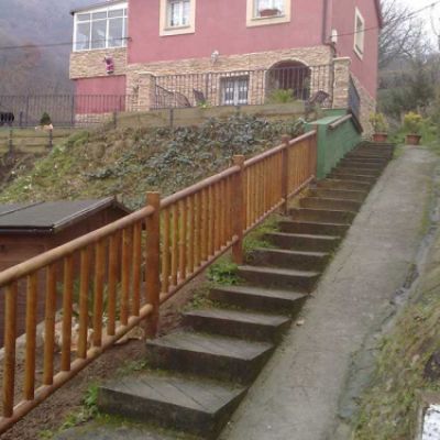 Entrada a vivienda con escaleras y barandilla de madera después de la obra