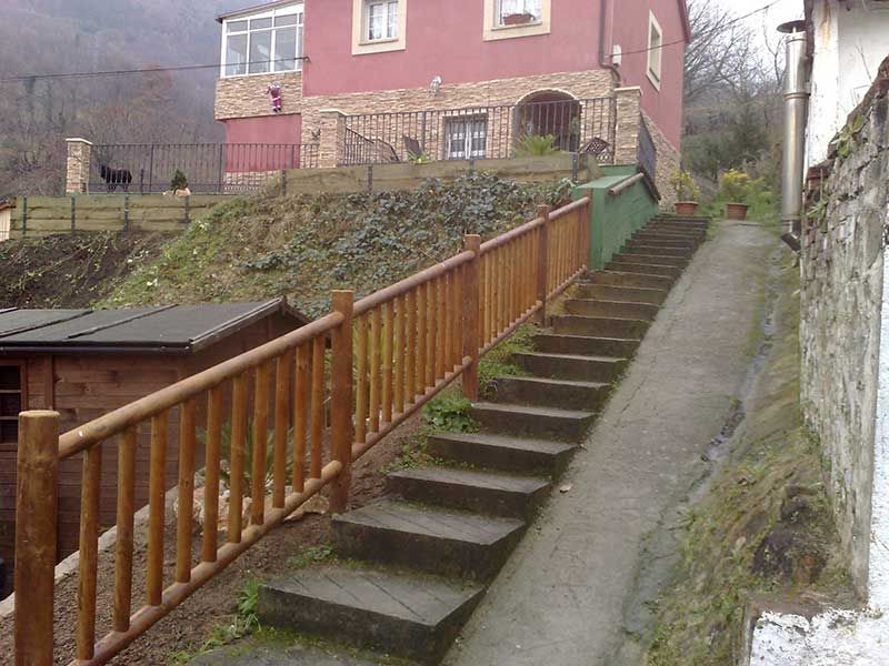 Entrada a vivienda con escaleras y barandilla de madera después de la obra
